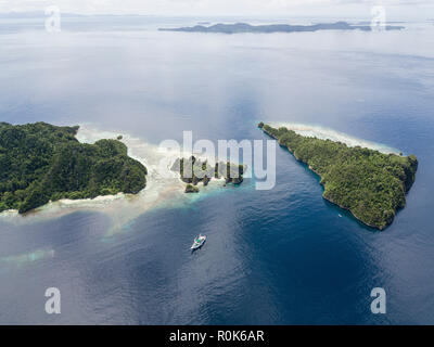 A Pinisi schooner sits at anchor in a remote area of Raja Ampat in eastern Indonesia. Stock Photo