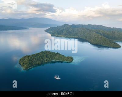 A Pinisi schooner sits at anchor in a remote area of Raja Ampat in eastern Indonesia. Stock Photo