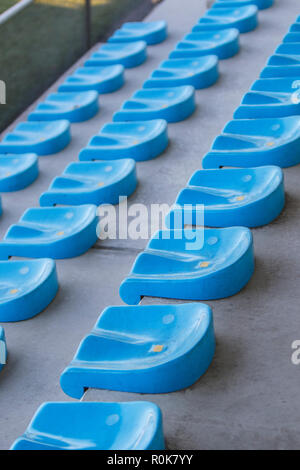 Empty blue plastic chairs in a row at the football stadium. Stock Photo