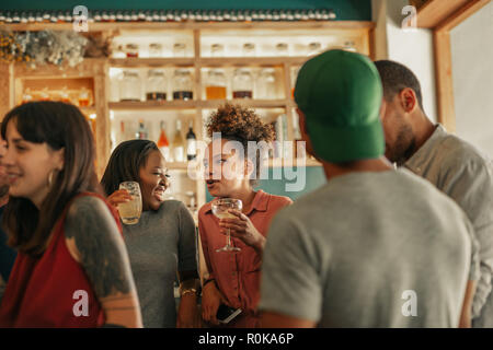 Two friends talking and laughing together in a busy bar Stock Photo