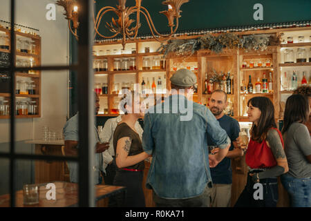 Group of friends standing in a bar having drinks together Stock Photo