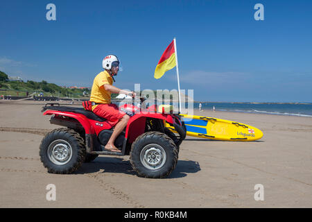 A lifeguard on a quad bike watching bathers on the beach at Scarborough in North Yorkshire Stock Photo