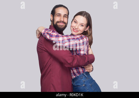 Portrait of happy satisfied bearded man and woman in casual style standing and hugging each other and looking at camera with toothy smile. indoor stud Stock Photo