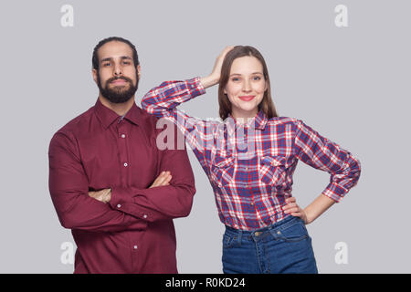 Portrait of satisfied bearded man with black collected hair and woman in casual style standing, smiling and looking at camera with crossed hands. indo Stock Photo