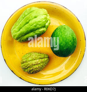 Top view of three green vegetables on yellow ceramic plate, isolated on white background Stock Photo