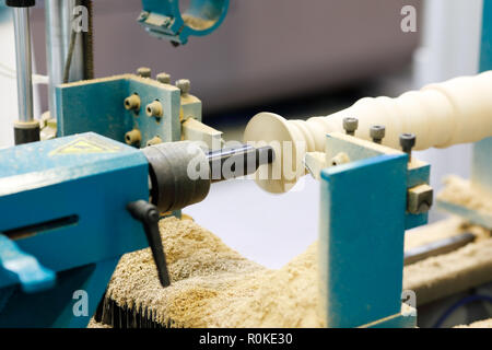 Carving a banister pillar in woodturning lathe machine. Selective focus. Stock Photo