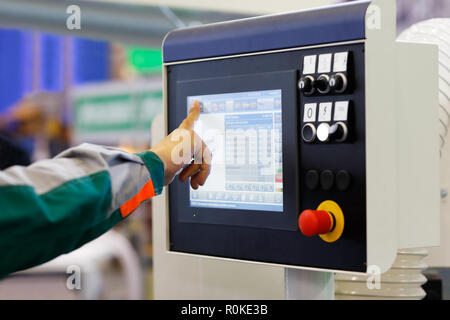 Operator using touchscreen prepares industrial equipment with CNC for a new task. Selective focus. Stock Photo