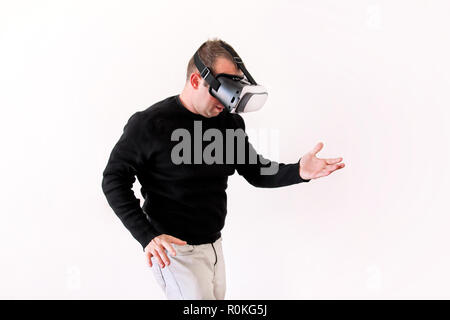 Man wearing and playing mobile game app on device virtual reality glasses on white background. Business man at office action and using vr box. Stock Photo