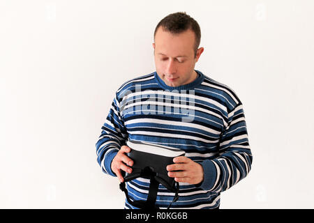 Man wearing and playing mobile game app on device virtual reality glasses on white background. Man action and using in virtual headset, VR box. Stock Photo