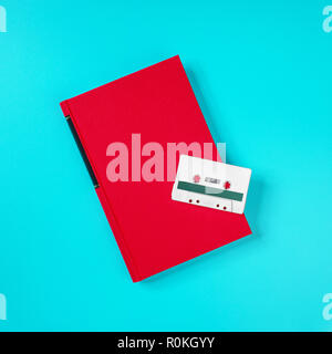 Retro white plastic audio cassette and red book laying on the green metal table Stock Photo