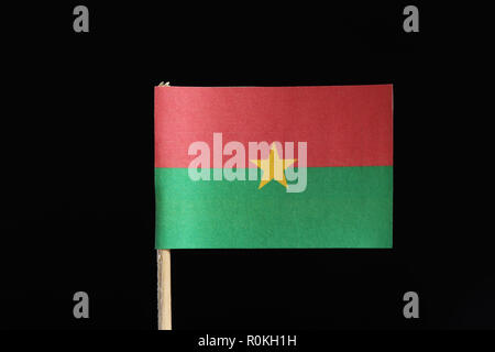 A official and original flag of Burkina Faso on toothpick on black background. Consists from two horizontal bands of red and green with yellow star in Stock Photo