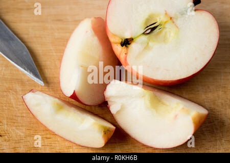 Close up of a sliced red apple on a wooden table with kitchen knife Stock Photo
