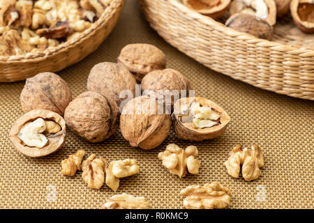 Walnuts on golden background. Walnut kernels in wicker basket. Stock Photo