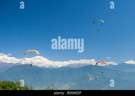 Tandem paragliders float over Nepal with the Annapurna Himalayas in the background Stock Photo