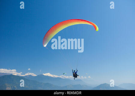 Tandem paragliders float over Nepal with the Annapurna Himalayas in the background Stock Photo