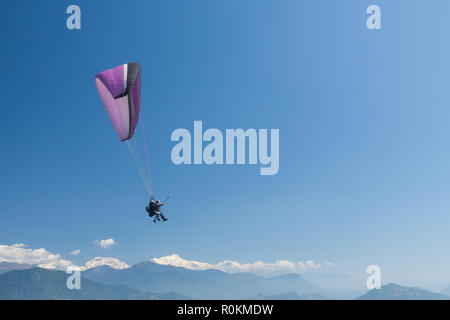 Tandem paragliders float over Nepal with the Annapurna Himalayas in the background Stock Photo