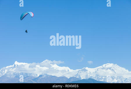 Tandem paragliders float over Nepal with the Annapurna Himalayas in the background Stock Photo