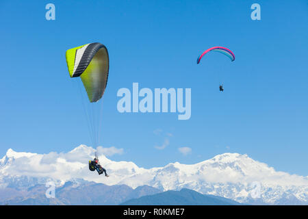 Tandem paragliders float over Nepal with the Annapurna Himalayas in the background Stock Photo