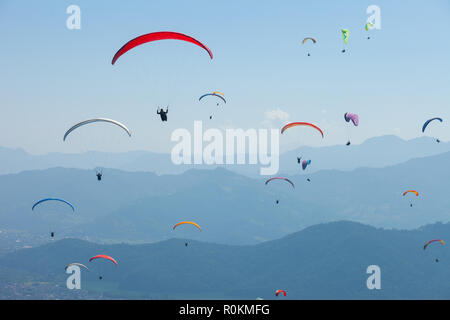 A large group of paragliders enjoy a thermal updraft in the Nepal Himalayas Stock Photo