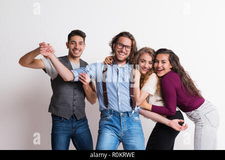 Portrait of joyful young friends standing in a studio, enjoying a party. Stock Photo