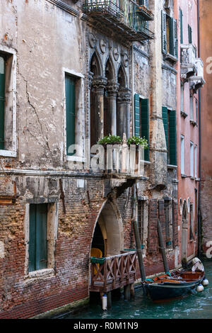 Old brick and painted buildings with balconies and doorways with gondala boats on the canals of Venice Italy Stock Photo
