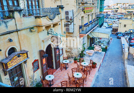 GHAJNSIELEM, MALTA - JUNE 15, 2018: The coastal neighborhood, surrounding the Mgarr Harbour, is occupied with cozy outdoor cafes and family restaurant Stock Photo