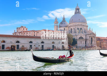 Venice, Italy - August 22, 2018: Gondolier in a gondola in front of Basilica Santa Maria della Salute Stock Photo