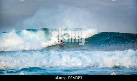 Surfer gets up on a wave. The wave twists with foam and splashes. Stock Photo