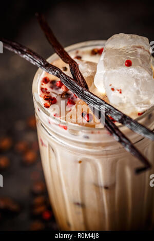 Close up of tall glass iced coffee latte with pink peppercorn and vanilla Stock Photo