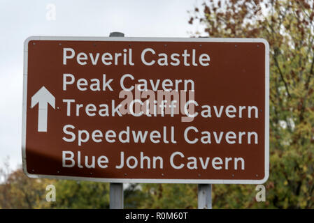 A tourist road sign of a list of four caverns and a castle ruin at  Castleton village in the Peak District of Derbyshire in the East Midlands of Engla Stock Photo