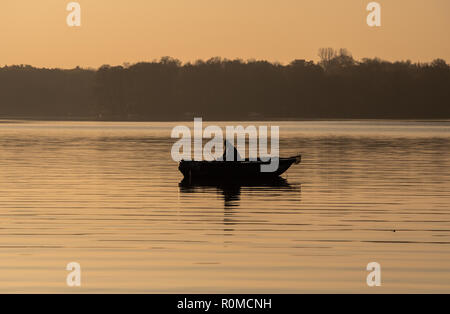 Berlin, Germany. 06th Nov, 2018. A man sits in a boat early in the morning and fishes. Credit: Paul Zinken/dpa/Alamy Live News Stock Photo