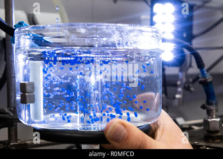 Holzminden, Germany. 23rd Oct, 2018. An employee of Symrise AG holds a container when 'ActiPearls' drip at the encapsulation system. Symrise is one of the world's leading suppliers of fragrances and flavors. Credit: Swen Pförtner/dpa/Alamy Live News Stock Photo