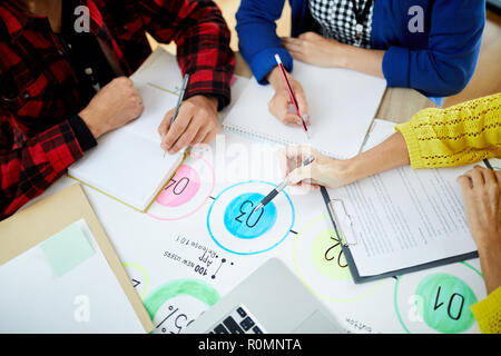 Hands of colleagues during discussion of development scheme while working over new project Stock Photo