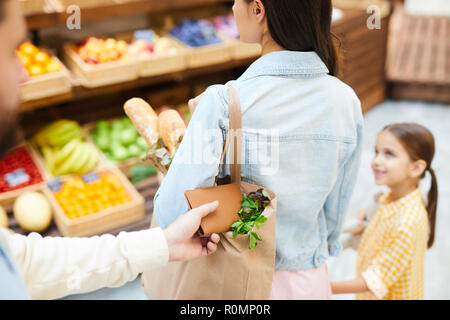 Close-up of man stealing wallet from bag of young lady walking with daughter in fresh food shop, thief taking purse out of shopping bag Stock Photo