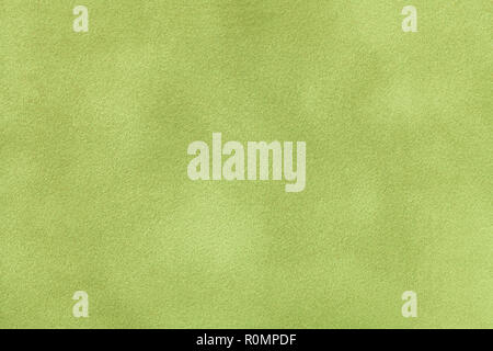 Light green matte background of suede fabric, closeup. Velvet texture of seamless olive leather. Stock Photo