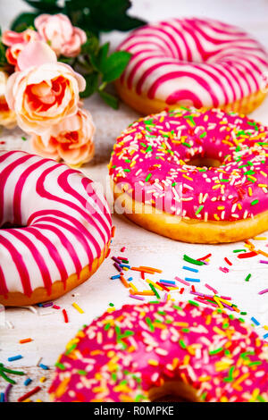 Pink donuts and rose on a wooden background. Delicious dessert. Stock Photo