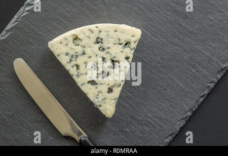 Blue cheese isolated on black slate board - Roquefort type cheese background top view close up photo Stock Photo