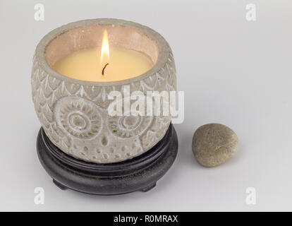 Owl shape decorative candle lit, with pebble next to it isolated on white background Stock Photo