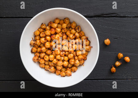 Chickpeas with olive oil and chili flakes - Spicy chickpeas in white bowl on black rustic background - top view photo Stock Photo