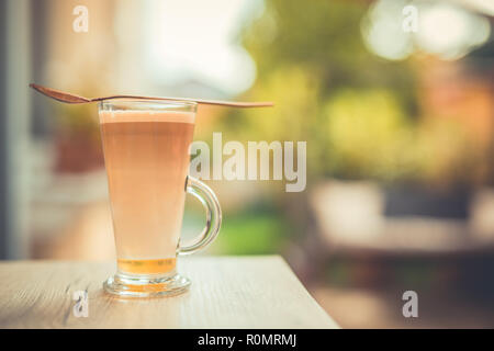 Relaxing morning closeup, coffee on wooden table top in long glass. Latte for morning motivation and day start Stock Photo