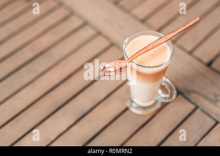 Relaxing morning closeup, coffee on wooden table top in long glass. Latte for morning motivation and day start Stock Photo