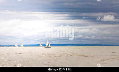 Boat sailing in the upcomming storm. Sailboat in bad weather sail at opened sea. Sailing yacht under heavy cloud sky. Stock Photo