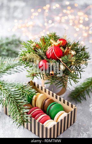 Variety of sweet macaroons in carton box. Fir branches on a gray background. Merry Christmas card. New year mood Stock Photo