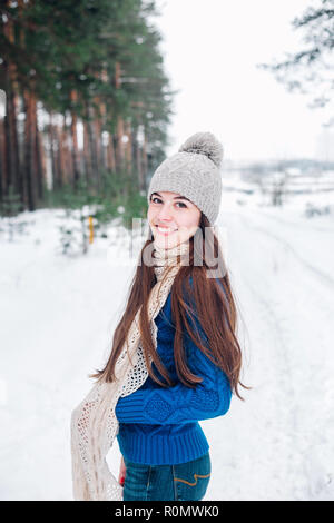 Winter portrait of young beautiful brunette woman wearing knitted snood covered in snow. Snowing winter concept. Stock Photo