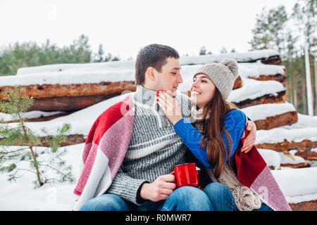 Portrait of happy young couple enjoying picnic in snowy winter park Stock Photo