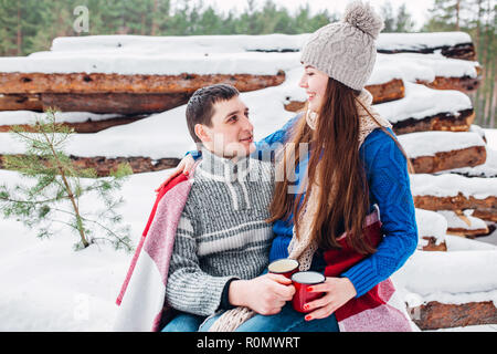 Portrait of happy young couple enjoying picnic in snowy winter park Stock Photo