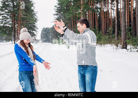 Snowball fight. Winter couple having fun playing in snow forest. Young joyful happy multi-racial couple. Stock Photo