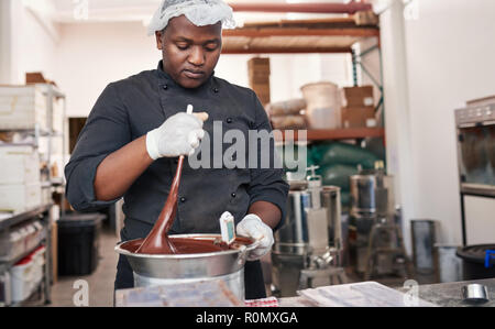 Worker using a bain marie to mix melting chocolate Stock Photo