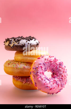 Pile of colorful donuts on pink background. Stock Photo