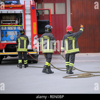 Italia, Italy - May 10, 2018: three Italian firefighters and the fire truck  with uniform and text Vigili del fuoco that means Firemen in Italian lang Stock Photo